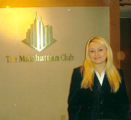 Women standing by The Manhattan Club logo